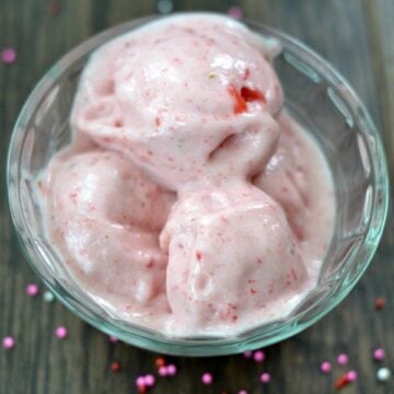 closeup of 2 ingredient Homemade Strawberry Ice Cream in a glass bowl with silver spoon and with text overlay