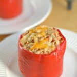closeup of a red pepper stuffed with a mixture of brown rice, ground turkey on a white plate