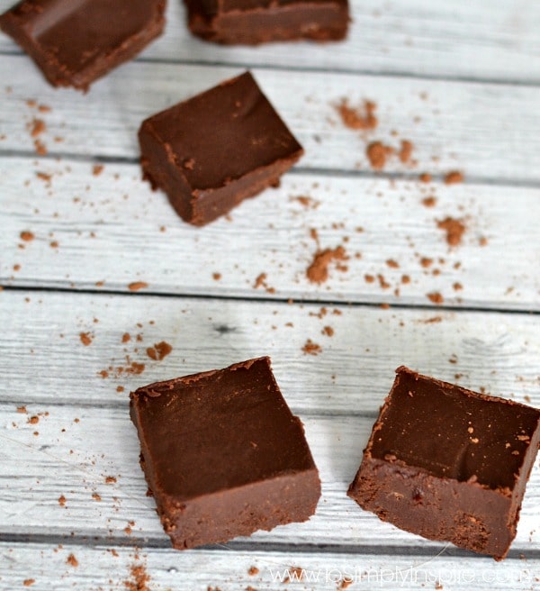 5 pieces of healthy chocolate fudge on a light gray table with cocoa powder