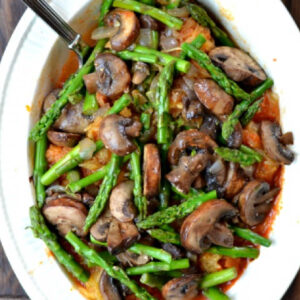 white bowl full of spaghetti squash primavera mixed with asparagus, mushrooms