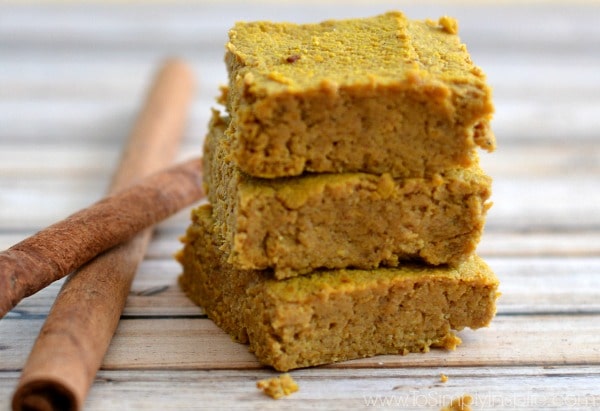 close-up of 3 Pumpkin Pie Bars stacked on top of each other beside 2 cinnamon sticks