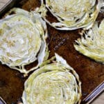 four cabbage steaks on a baking sheet