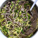 a pan full of zucchini noodles and strips of beef in a teriyaki sauce