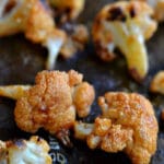 several pieces of buffalo flavored cauliflower florets on a baking sheet