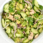closeup of avocado tuna salad with cucumbers and red onion in a white bowl