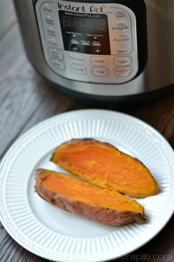 closeup of sweet potato cut open on white plate with an instant pot in background