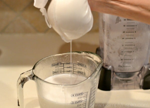 coconut milk being squeezed into a measuring cup from a nut bag