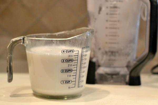 homemade coconut milk in a measuring cup with a pitcher in the background