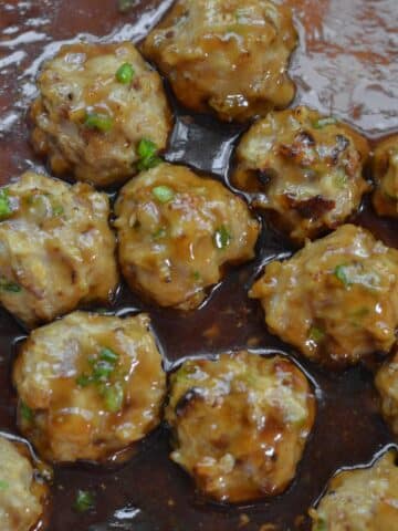 Closeup of a panful Teriyaki Chicken Meatballs Recipe in a brown sauce.