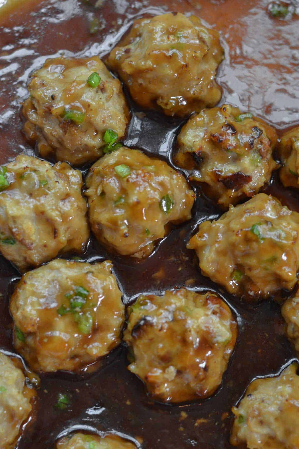 Closeup of a panful Teriyaki Chicken Meatballs Recipe in a brown sauce.