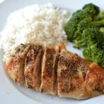 Baked Chicken breast on a white plate with rice and broccoli