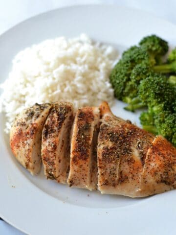 Baked Chicken breast on a white plate with rice and broccoli