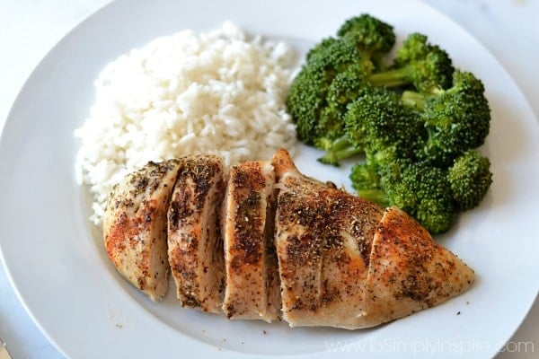 Baked Chicken breast on a white plate with broccoli and rice as side dishes  