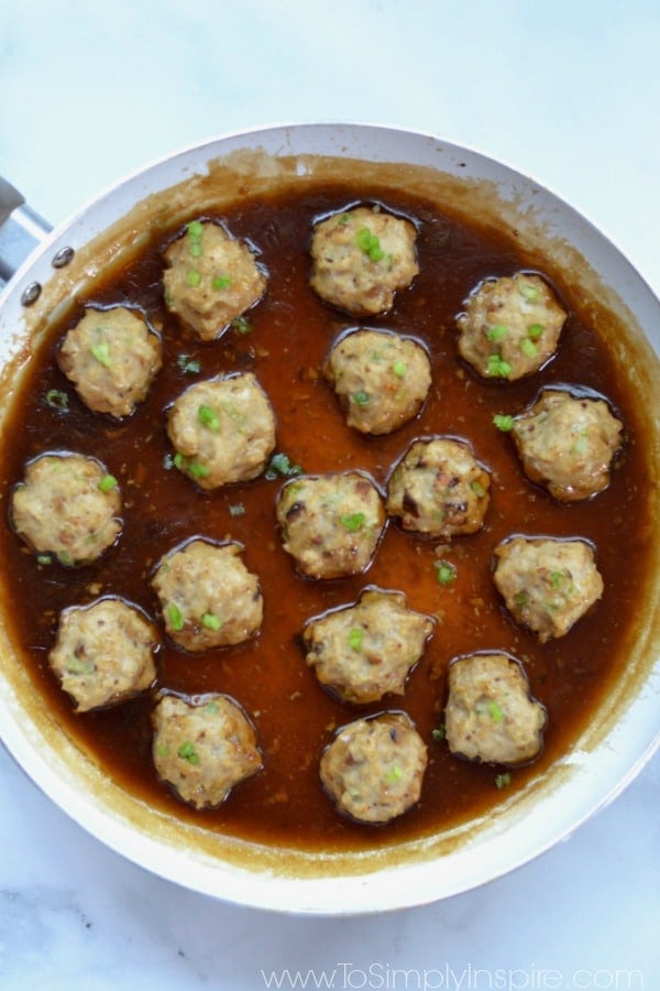 Closeup of seventeen Teriyaki Chicken Meatballs in a saute pan. 