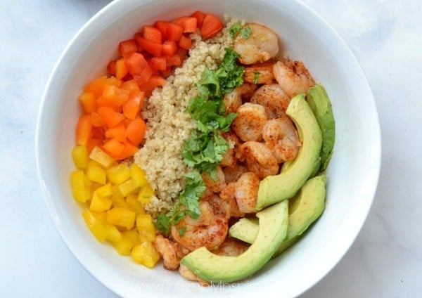 closeup of Shrimp, quinoa, sliced avocado and diced red, yellow, orange peppers