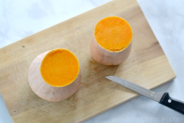 butternut squash cut in half on a wood cutting board with a knife beside