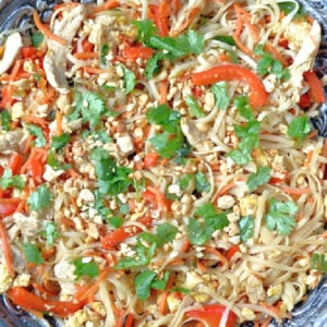 homemade chicken pad thai in a silver bowl topped with peanuts and cilantro pieces