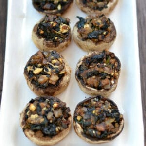 closeup of 6 stuffed mushrooms on a white plate