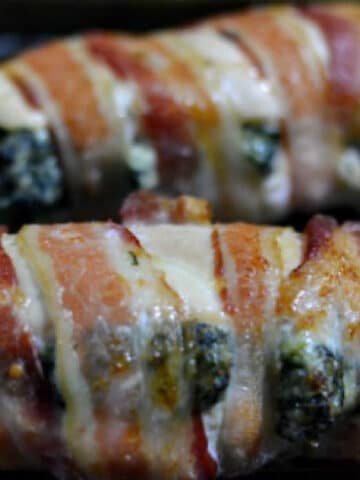 closeup of chicken breast stuffed with spinach and cream sheese mixture and then wrapped in bacon