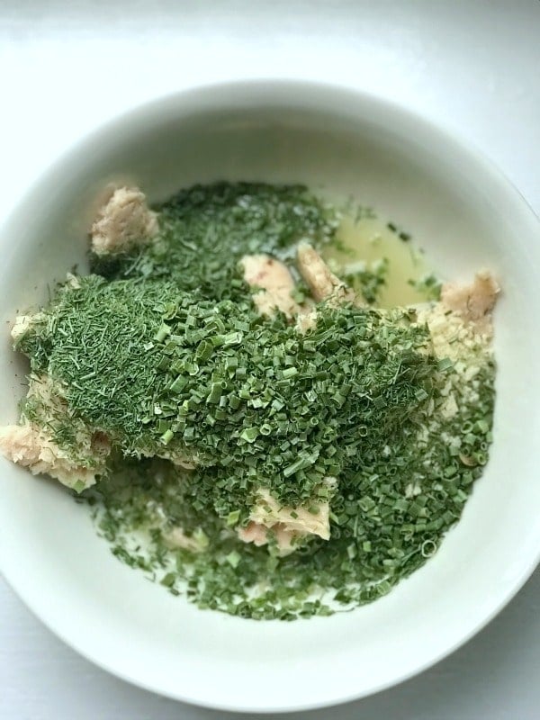 A close up of a bowl of food with tuna with dill covering