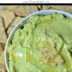 closeup of avocado hummus in a white bowl with text overlay