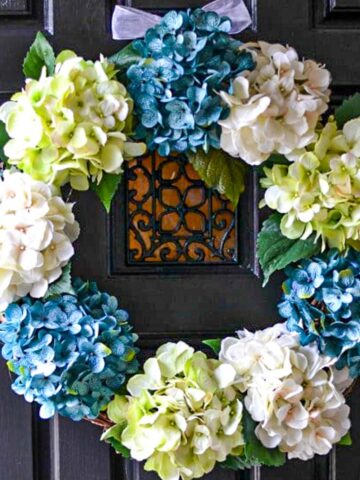 hydrangea wreath with blue, white and pale green flowers on a black door