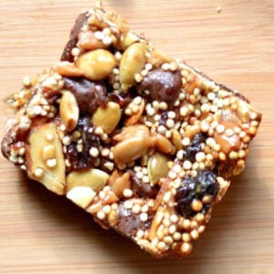 square energy bar with pumpkins seeds, raisins, quinoa, dates on a wood table