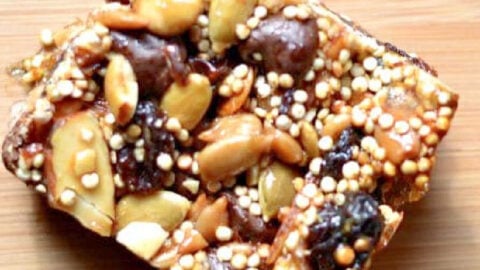 square energy bar with pumpkins seeds, raisins, quinoa, dates on a wood table