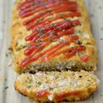 closeup of turkey meatloaf topped with ketchup and a slice cut off the end.