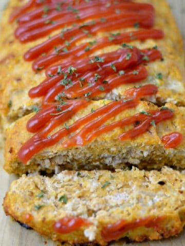 closeup of turkey meatloaf topped with ketchup and a slice cut off the end.
