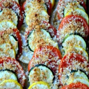 sliced zucchini, yelllow squash and tomatoes lined in a casserole dish and topped with breadcrumbs.