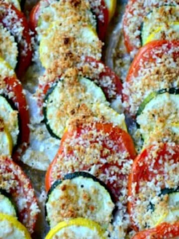 sliced zucchini, yelllow squash and tomatoes lined in a casserole dish and topped with breadcrumbs.