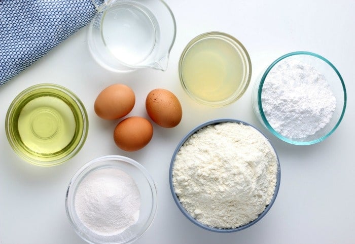 Bowls of ingredients for lemon cake on a table, eggs, flour, oil, sugar.