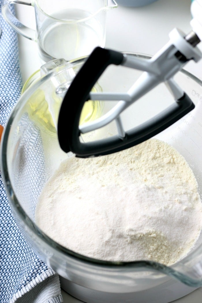 overhead picture of cake mix in a glass bowl with black mixer overtop