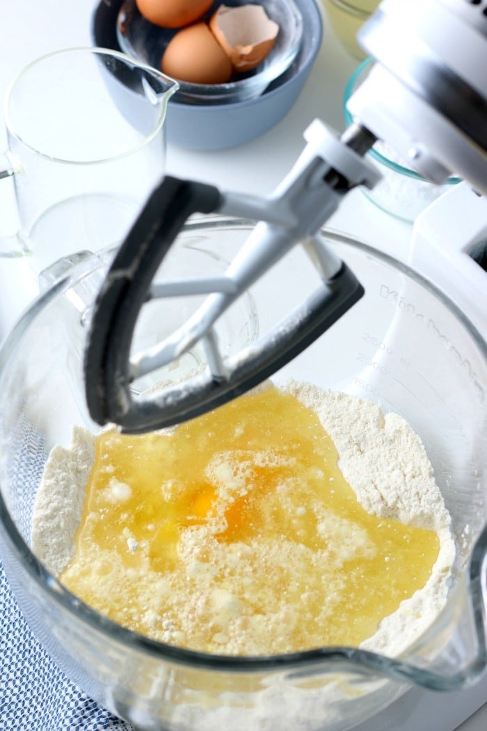 overhead picture of cake mix and eggs in a glass bowl with black mixer overtop