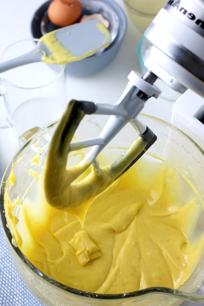overhead picture of lemon cake mix in a glass bowl with black mixer overtop