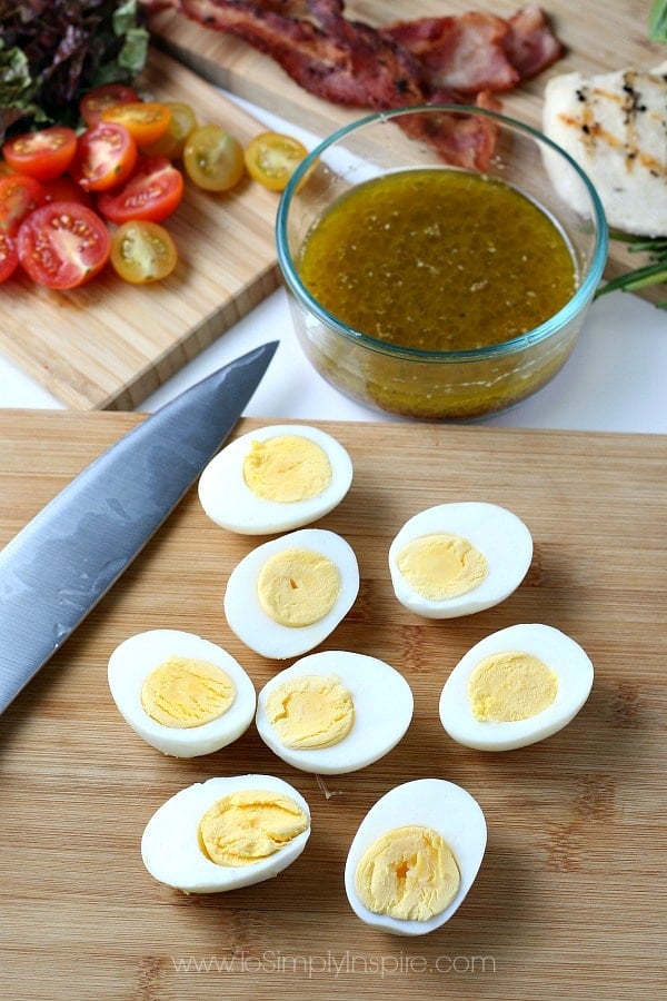 sliced hardboiled eggs on a wood cutting board with a knife