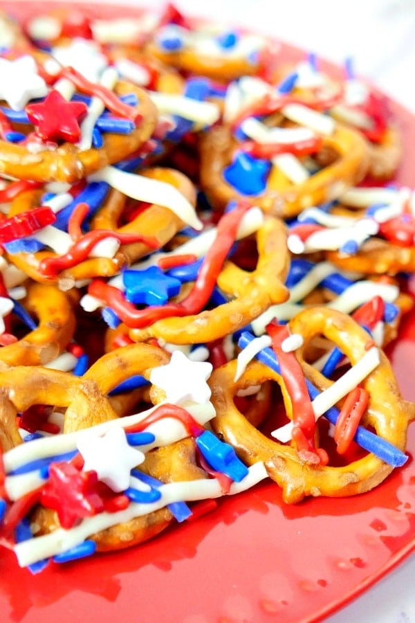 Patriotic Pretzels covered with red white and blue sprinkles on a red plate