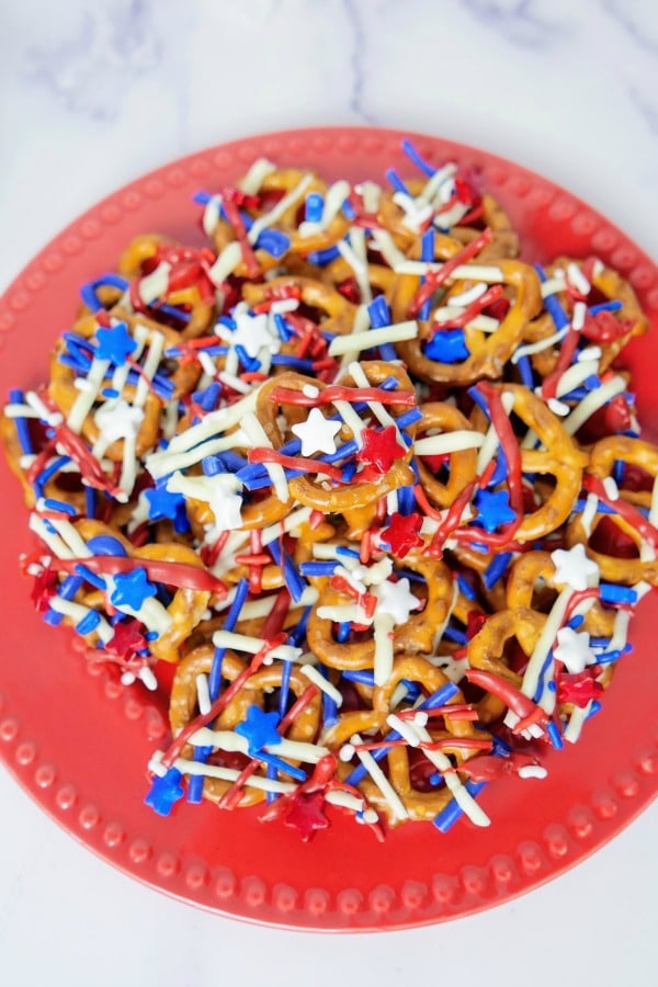 Patriotic Pretzels covered with red white and blue sprinkles on a red plate