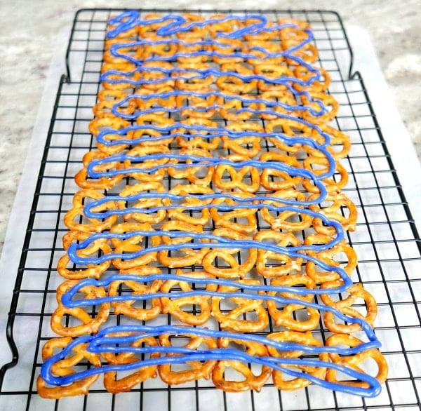 knot pretzels lined on a rack with blue icing drizzled overtop