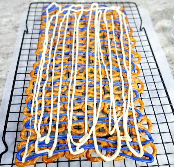 knot pretzels lined on a rack with blue and white icing drizzled overtop