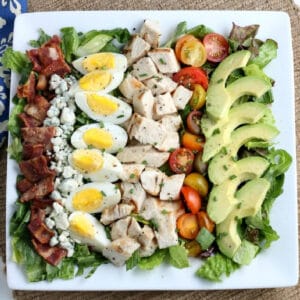 cobb salad with avocado, hard boiled eggs, chicken bacon and tomatoes lined in a row