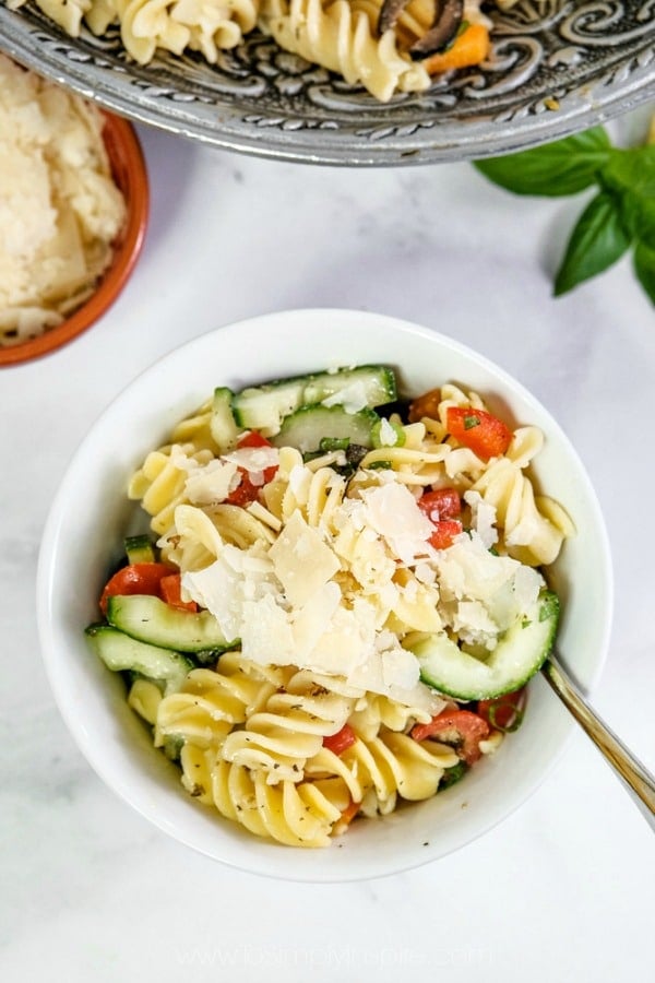 closeup of Italian Pasta salad in a white bowl topped with shaved parmesan cheese