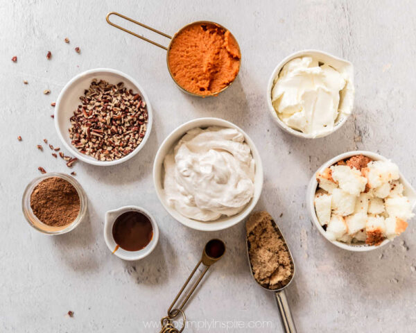 Several ingredients for pumpkin cheesecake trifles in measuring cups and bowls