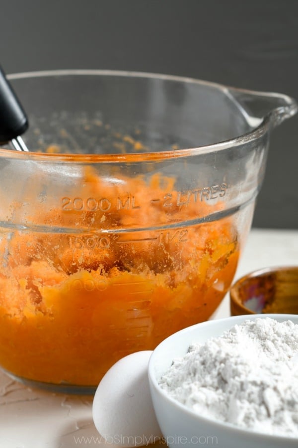 big measuring cup with mashed sweet potatoes and a bowl of white flour