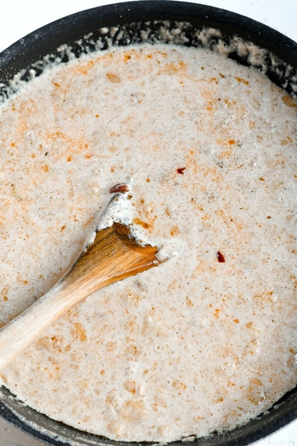 creamy sauce in a black pan with a wooden spoon