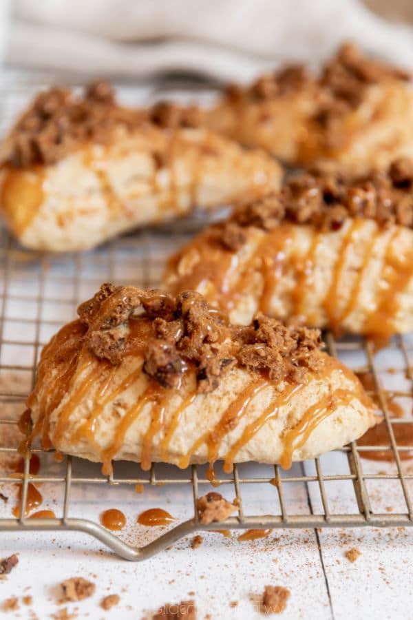 four scones drizzled with caramel sauce on a metal cooling rack