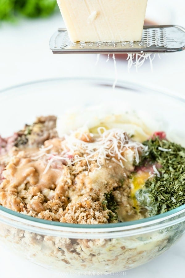 parmesan cheese being grated over meatloaf mixture