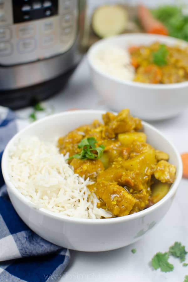 chicken curry and rice in a white bowl with an instant pot in the backgrond
