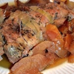 pork tenderloin surrounded by cooked apples on a white plate